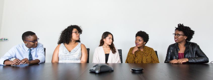 Women and men sitting at a table talking and having a conversation