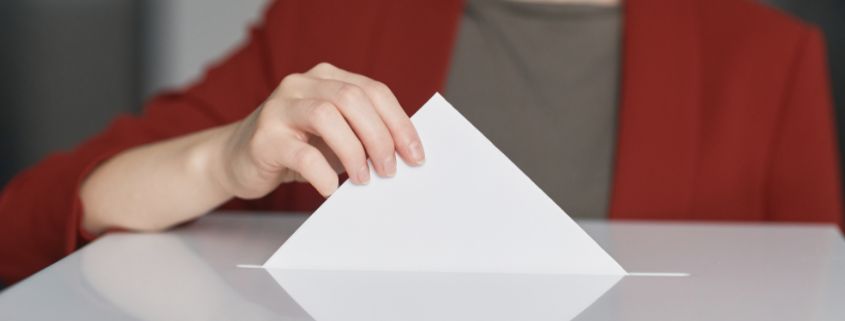 Women putting her vote on a paper and putting it in a box for votes to be collected